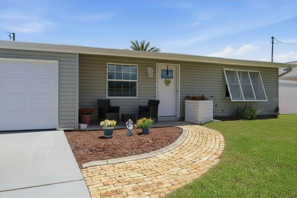 A single-story house with gray siding, a brick walkway, and a white garage door — 201 E TARPON BLVD NW, PORT CHARLOTTE, FL