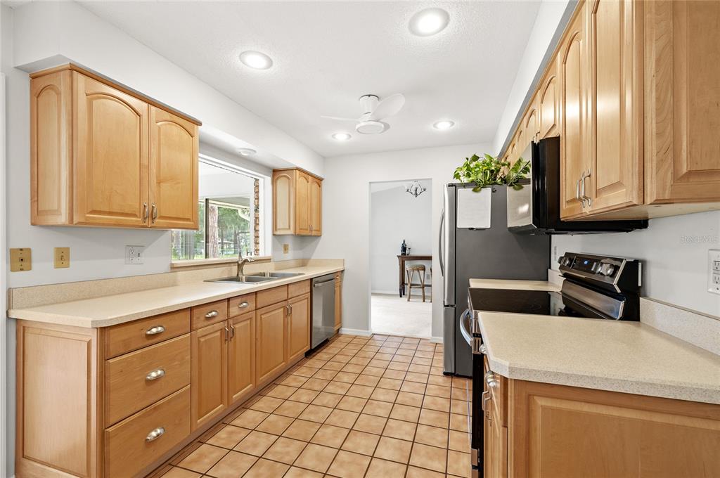 A kitchen with light wood cabinets, beige countertops, and tiled flooring — 109 CARDINAL LANE, EUSTIS, FL