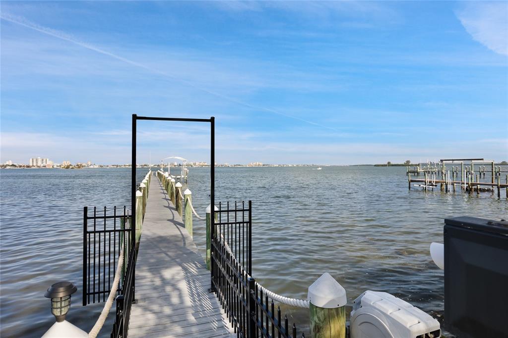 A wooden dock extends over the water, framed by black metal gates and railings — 202 FAIRMONT STREET, CLEARWATER, FL