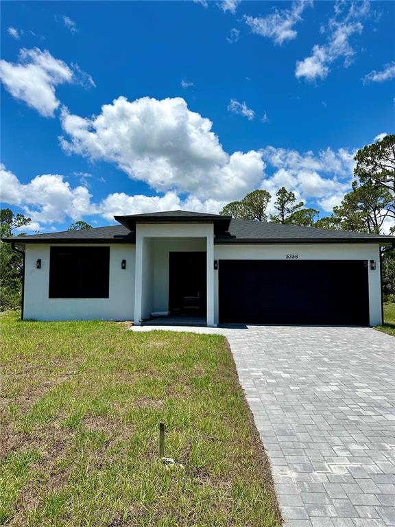 A single-story house with a white exterior, black garage door, and a paved driveway — 8533 LANCELOT AVENUE, NORTH PORT, FL