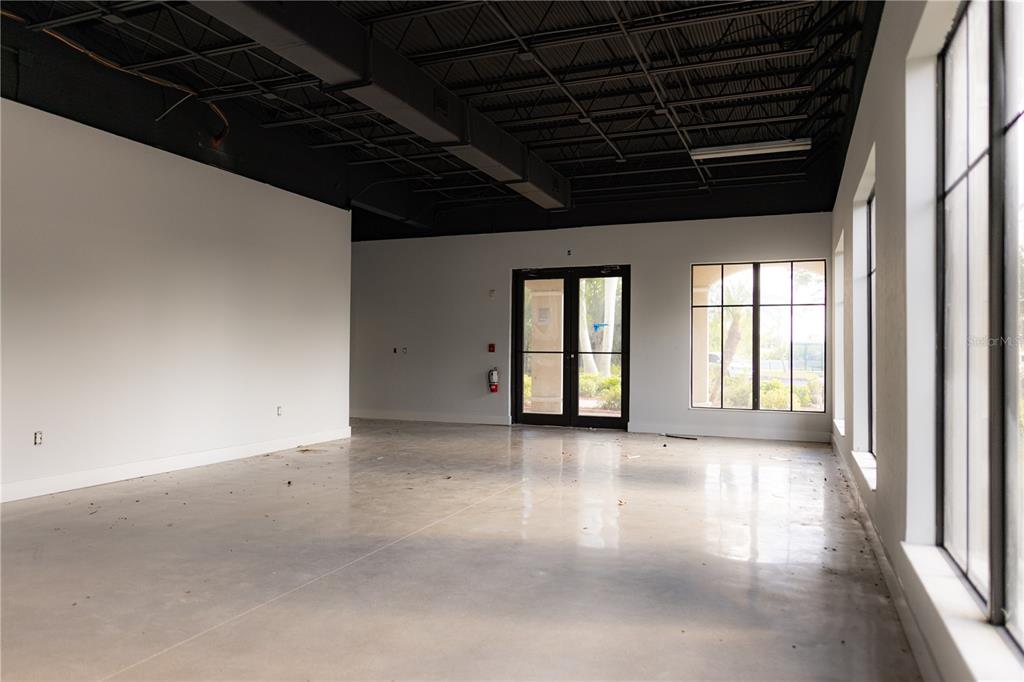 An empty commercial space features polished concrete floors, white walls, and an exposed black ceiling — 5920 PAN AMERICAN BOULEVARD UNIT 101, NORTH PORT, FL