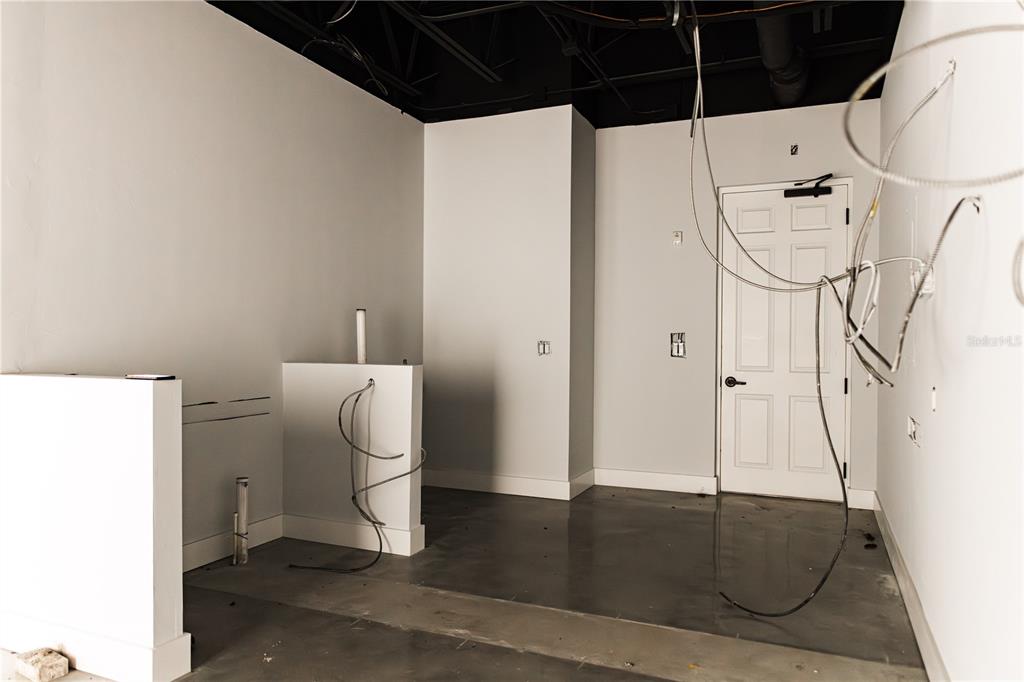 An unfinished commercial interior features white walls, a black exposed ceiling, and concrete flooring — 5920 PAN AMERICAN BOULEVARD UNIT 101, NORTH PORT, FL