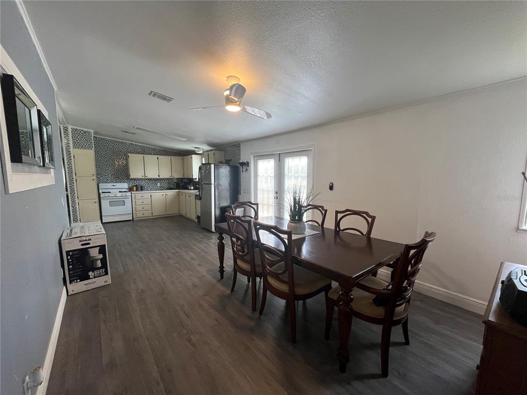 A dining area with a wooden table and chairs sits adjacent to an open kitchen — 10780 STATE ROAD 60 E, LAKE WALES, FL