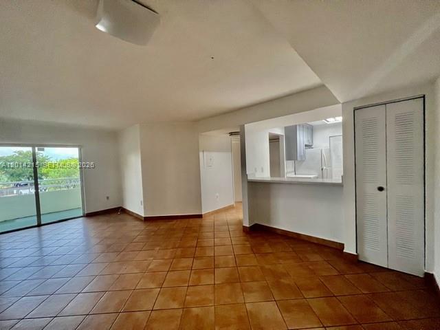 An open living area features brown tile flooring, a kitchen pass-through, and a sliding glass door — 10755 SW 108th Ave # 302, Miami FL 33176, MIAMI, FL