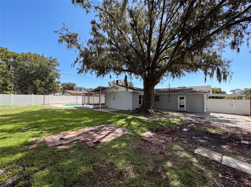 A large oak tree stands in the backyard of a house with a swimming pool — 1823 LORI LANE W, LAKELAND, FL