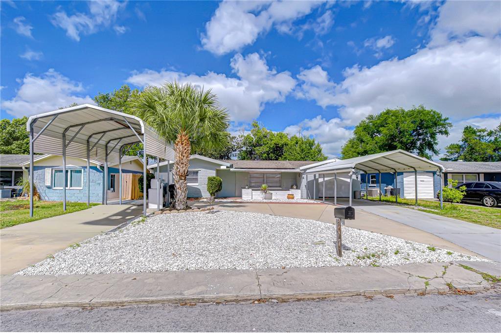 A single-story house features two metal carports and a white gravel front yard — 10901 OLDHAM ROAD, PORT RICHEY, FL