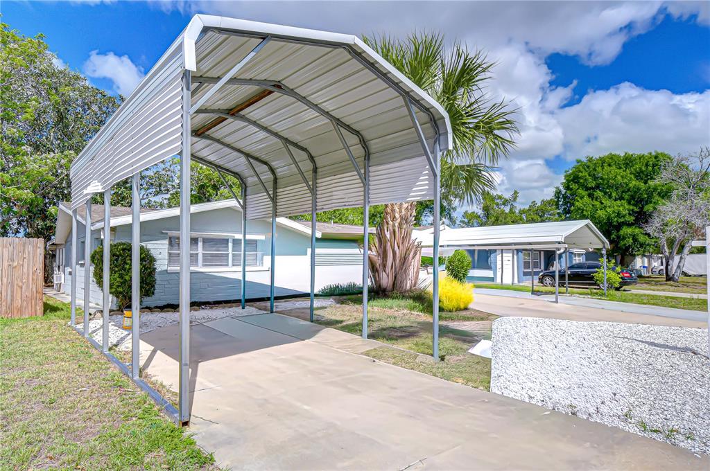 A metal carport stands over a concrete driveway in front of a single-story house — 10901 OLDHAM ROAD, PORT RICHEY, FL