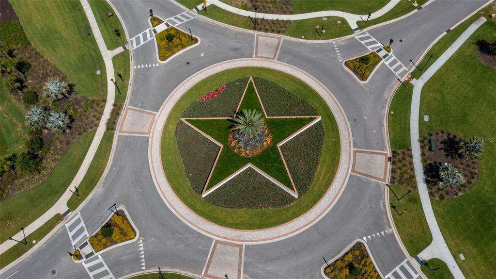 An aerial view shows a circular roundabout featuring a large star-shaped garden in the center — 3834 BUTTE TRAIL, LAKEWOOD RANCH, FL