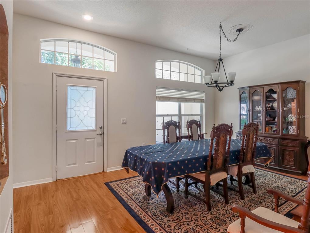 A dining room with a wooden table, chairs, hutch, and arched windows near the door — 10110 WHISPER POINTE DRIVE, TAMPA, FL