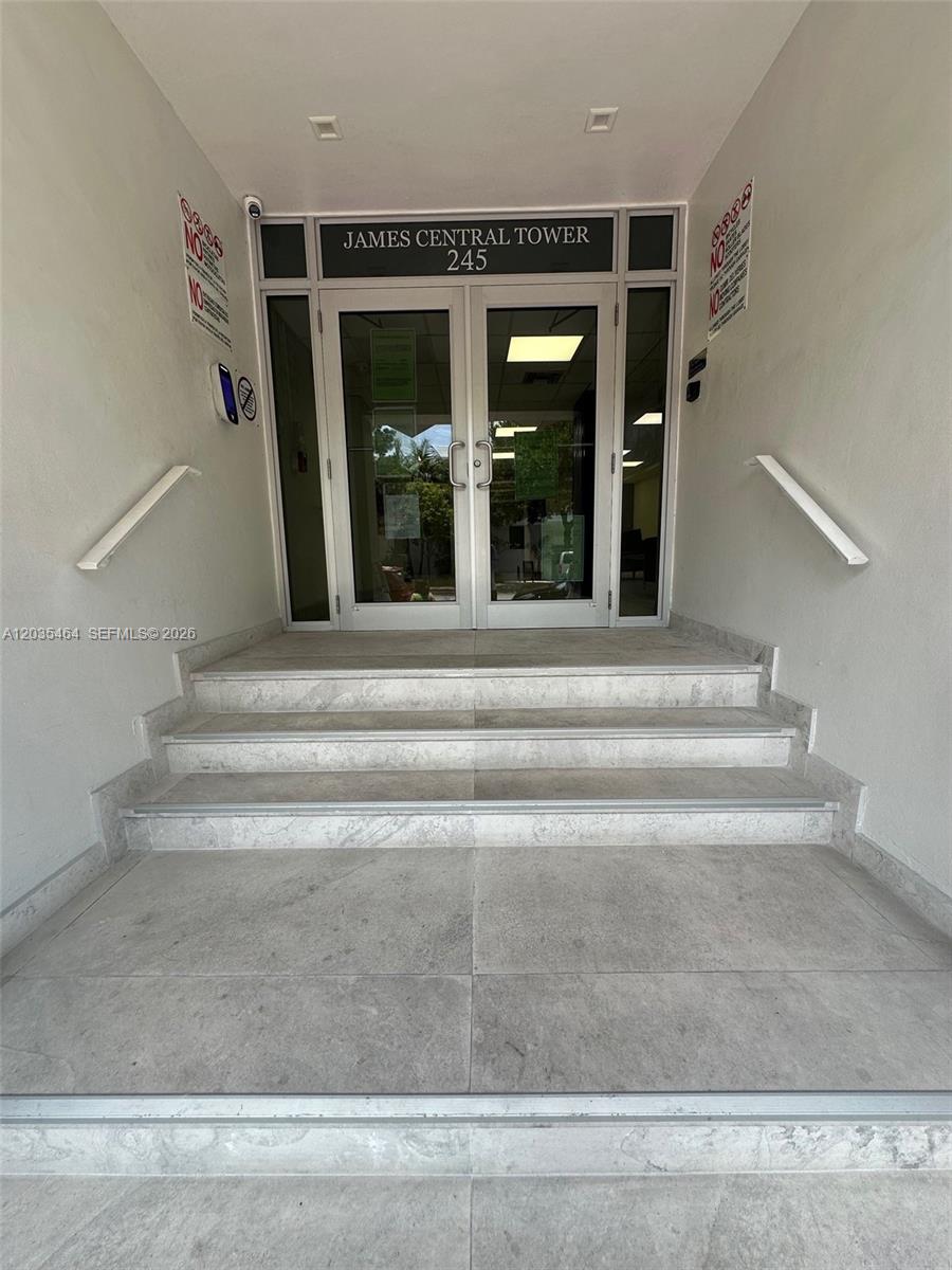 The entrance to a building features glass double doors, stone steps, and white walls — 245 18th St # 401, Miami Beach FL 33139, MIAMI BEACH, FL