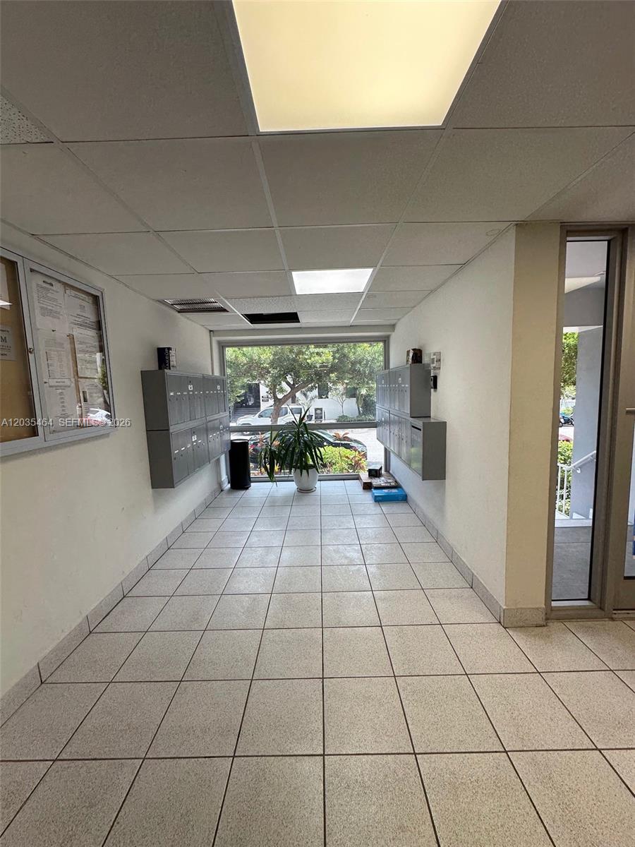 A mailroom features tiled floors, wall-mounted mailboxes, and a large window overlooking a parking area — 245 18th St # 401, Miami Beach FL 33139, MIAMI BEACH, FL