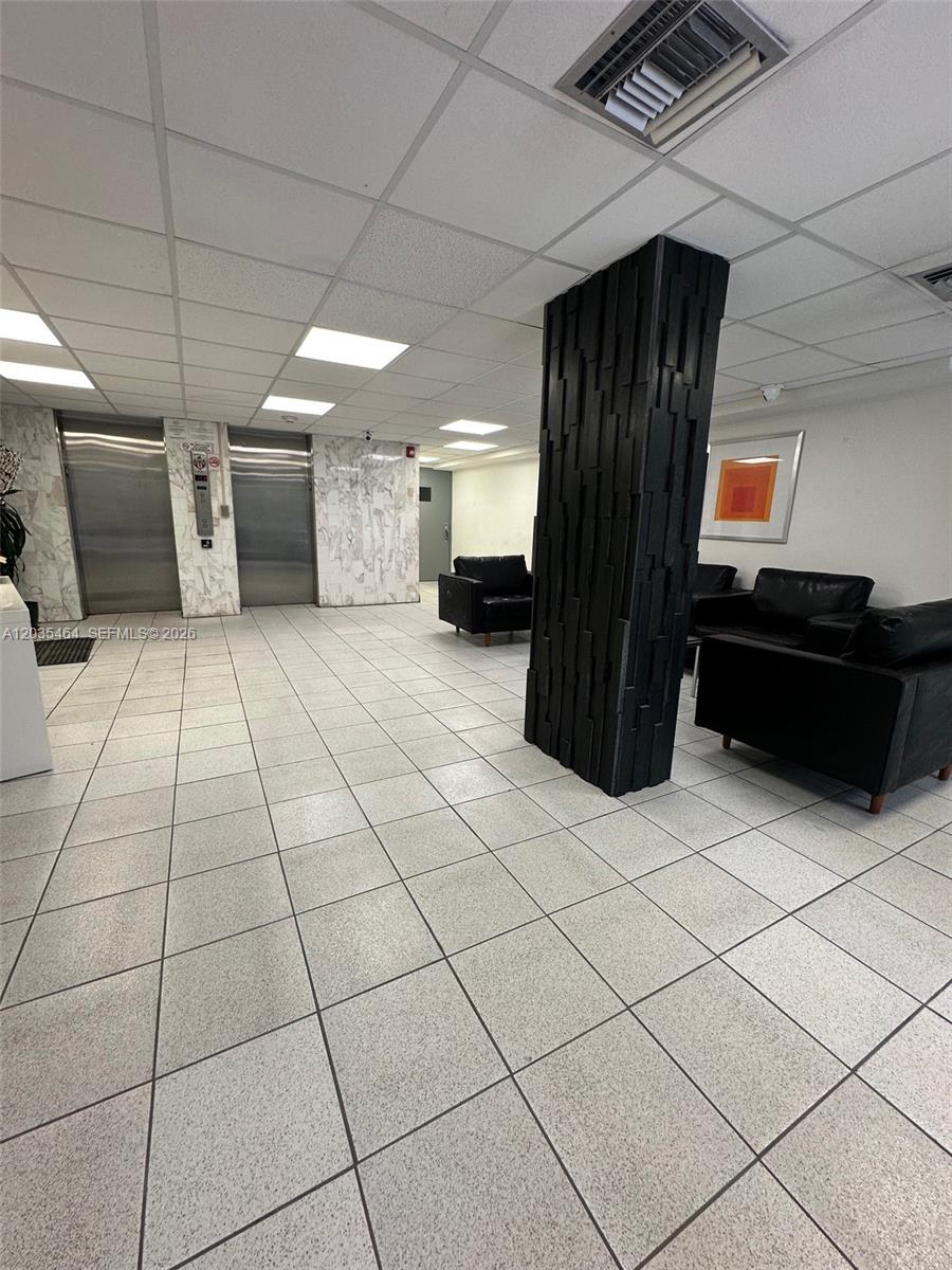 A lobby features a black textured pillar, black leather seating, and two stainless steel elevators — 245 18th St # 401, Miami Beach FL 33139, MIAMI BEACH, FL