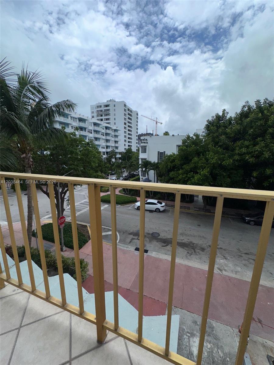 A view from a balcony overlooking a street with trees, buildings, and parked cars — 245 18th St # 401, Miami Beach FL 33139, MIAMI BEACH, FL
