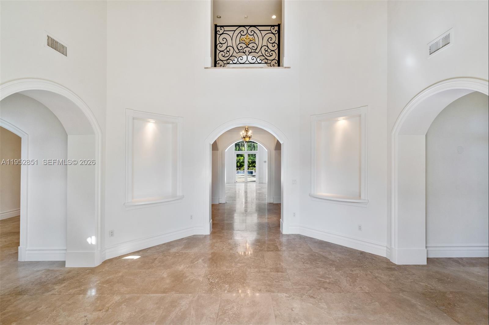 A bright, high-ceilinged foyer features arched doorways, recessed wall niches, and polished stone flooring — 6025 SW 108th St, Pinecrest FL 33156, PINECREST, FL