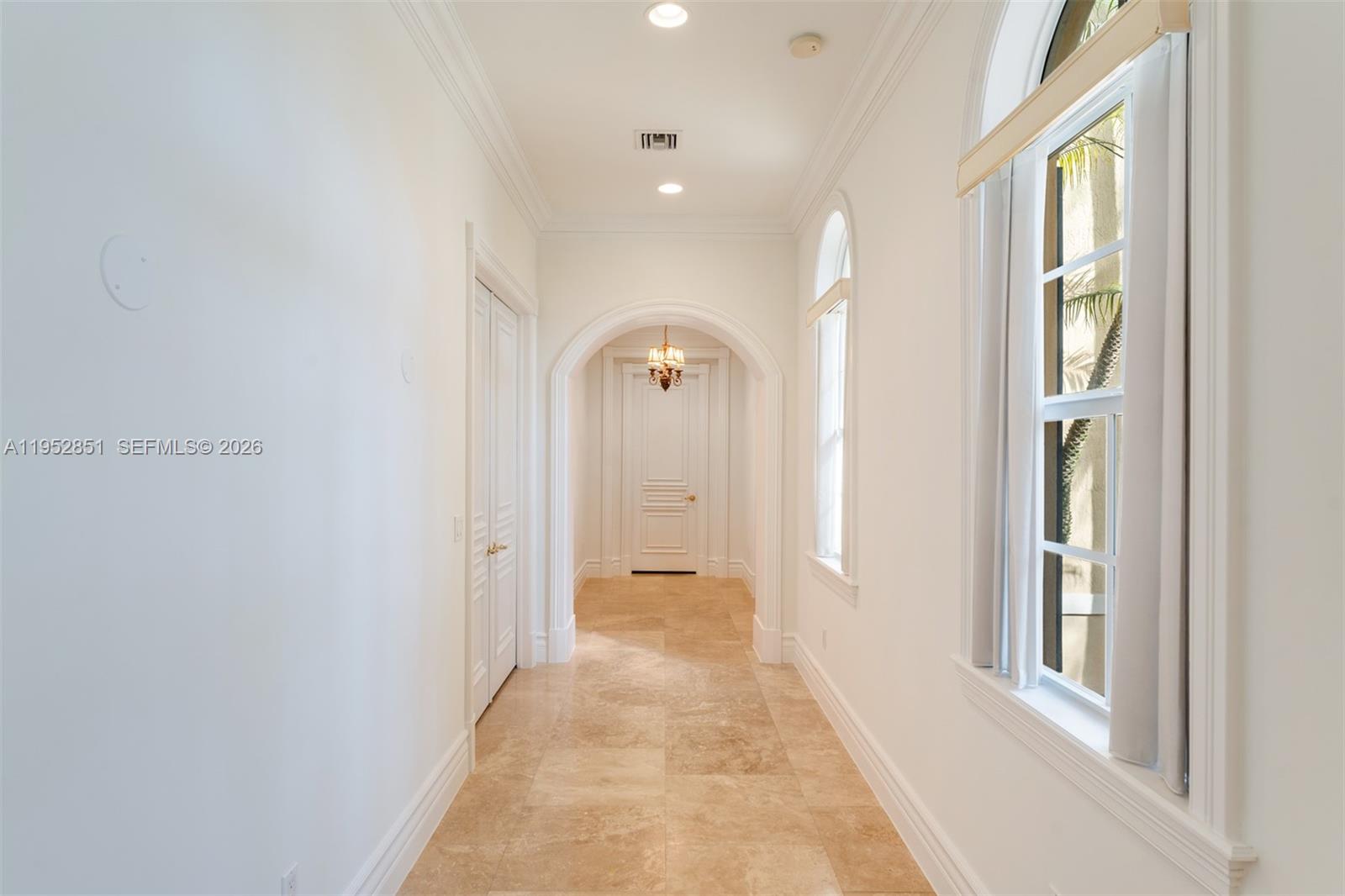 A bright hallway features white walls, arched doorways, tile flooring, and tall windows — 6025 SW 108th St, Pinecrest FL 33156, PINECREST, FL