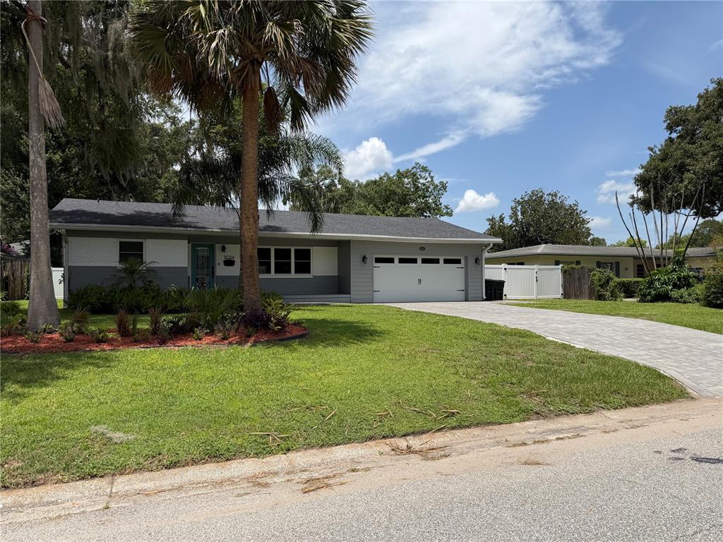 A single-story gray house with a white garage door, paved driveway, and palm tree — 5024 MORTIER AVENUE, ORLANDO, FL