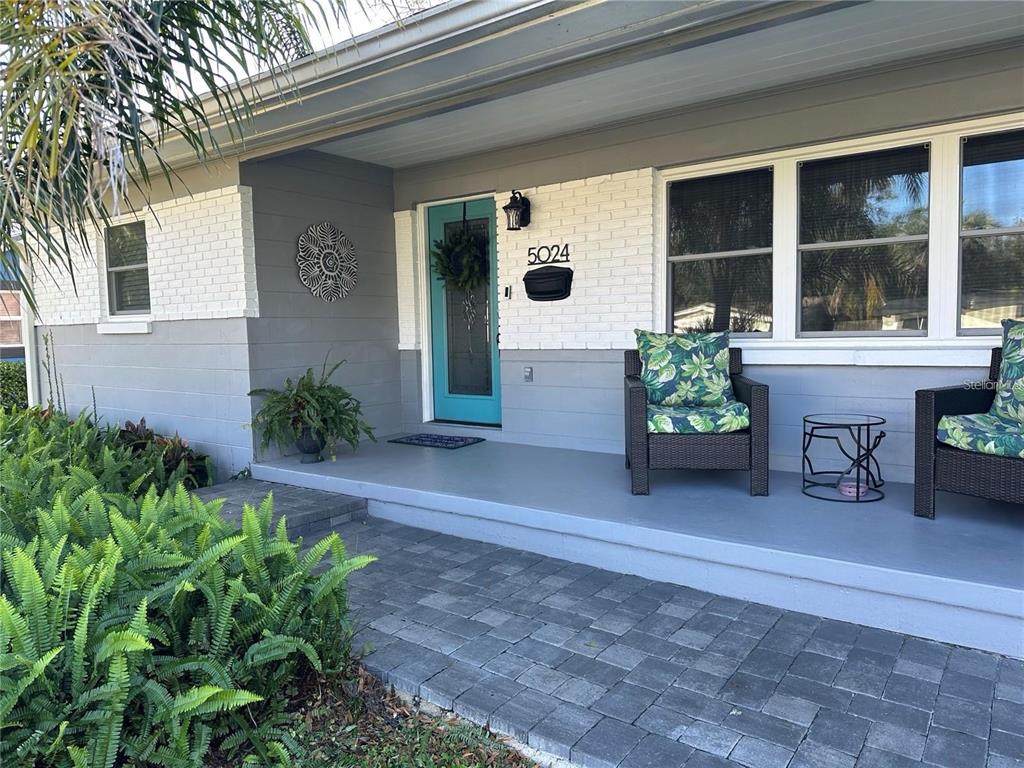 A front porch with gray painted concrete, a teal door, and two wicker chairs — 5024 MORTIER AVENUE, ORLANDO, FL