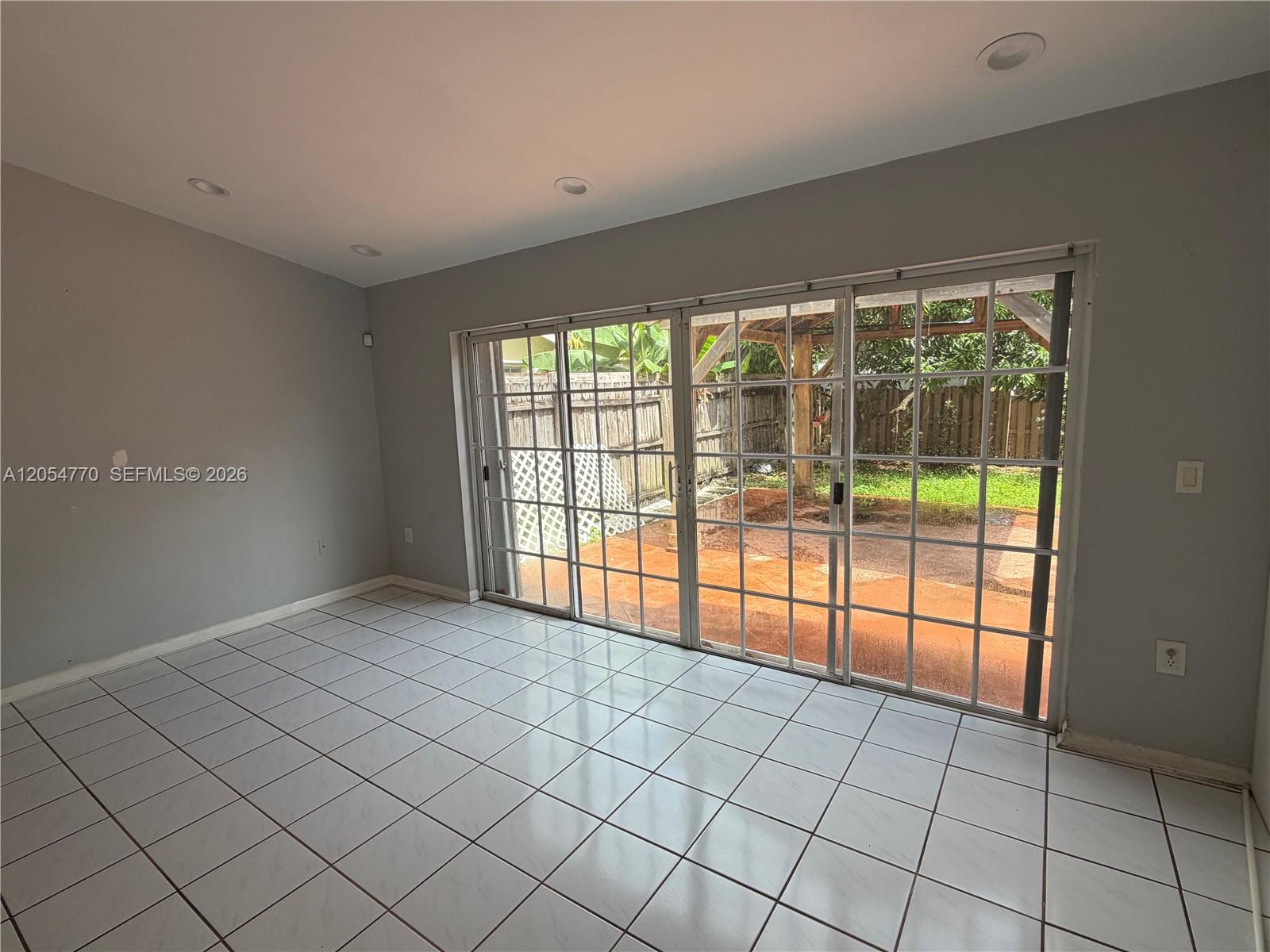 A room with white tile flooring and sliding glass doors leading to a backyard patio — 14444 SW 92nd Ter # 14444, Miami FL 33186, MIAMI, FL