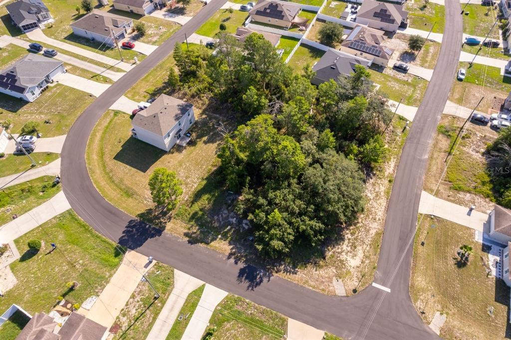 An aerial view shows a vacant wooded lot surrounded by suburban houses and paved streets — 174 MAPLE DRIVE, POINCIANA, FL