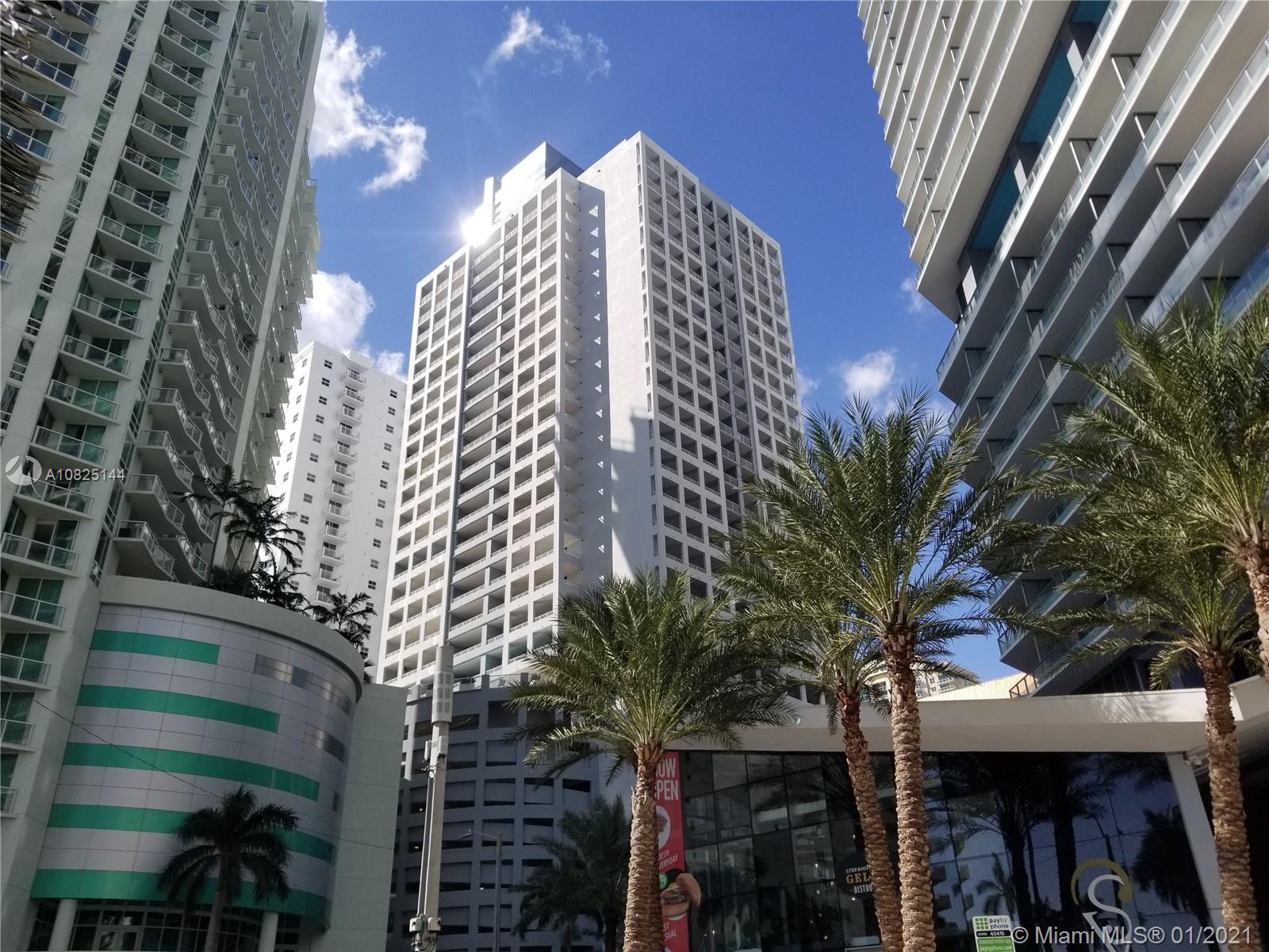 A low-angle view of several tall white apartment buildings surrounded by palm trees — 170 SE 14th St # 1507, Miami FL 33131, MIAMI, FL