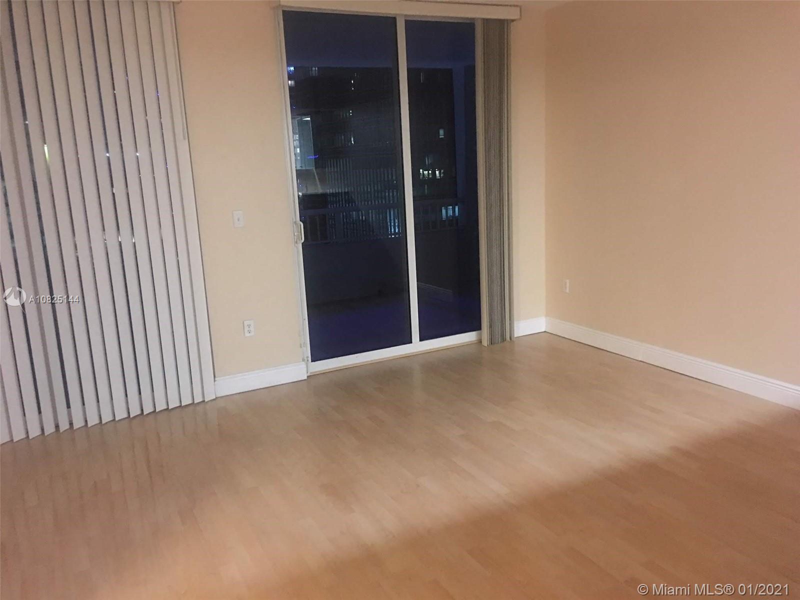 An empty room features light wood flooring, beige walls, and a sliding glass door — 170 SE 14th St # 1507, Miami FL 33131, MIAMI, FL