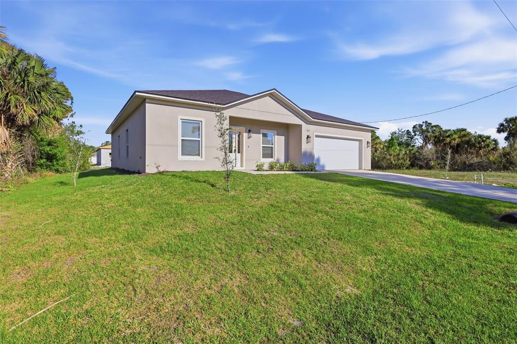 A single-story house with a beige stucco exterior, a two-car garage, and a grassy lawn — 3227 HALSEY AVENUE SE, PALM BAY, FL