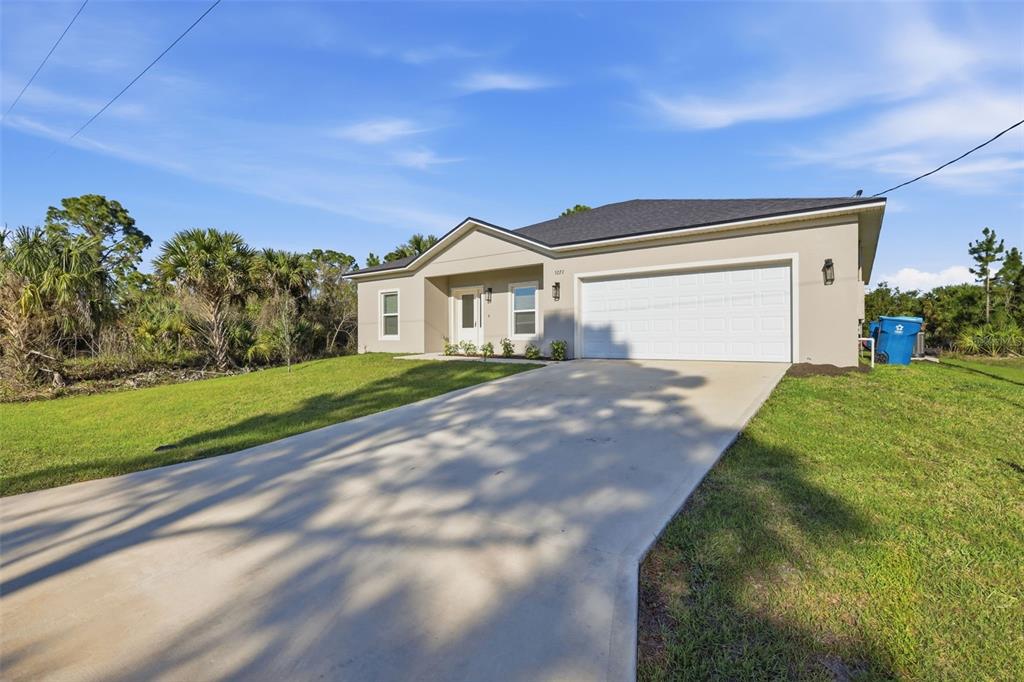 A single-story house with a beige stucco exterior, a two-car garage, and a concrete driveway — 3227 HALSEY AVENUE SE, PALM BAY, FL