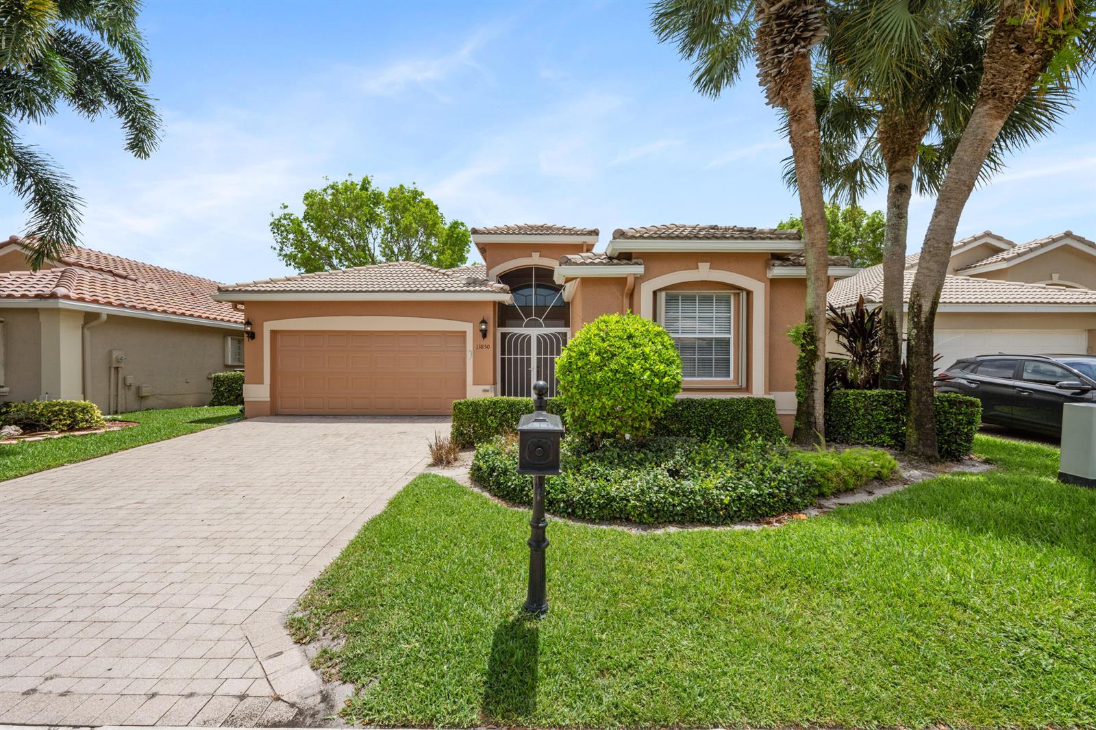 A single-story house with a tan stucco exterior, a tiled roof, and a paved driveway — 13850 Vía Vittoria, Delray Beach FL 33446, DELRAY BEACH, FL