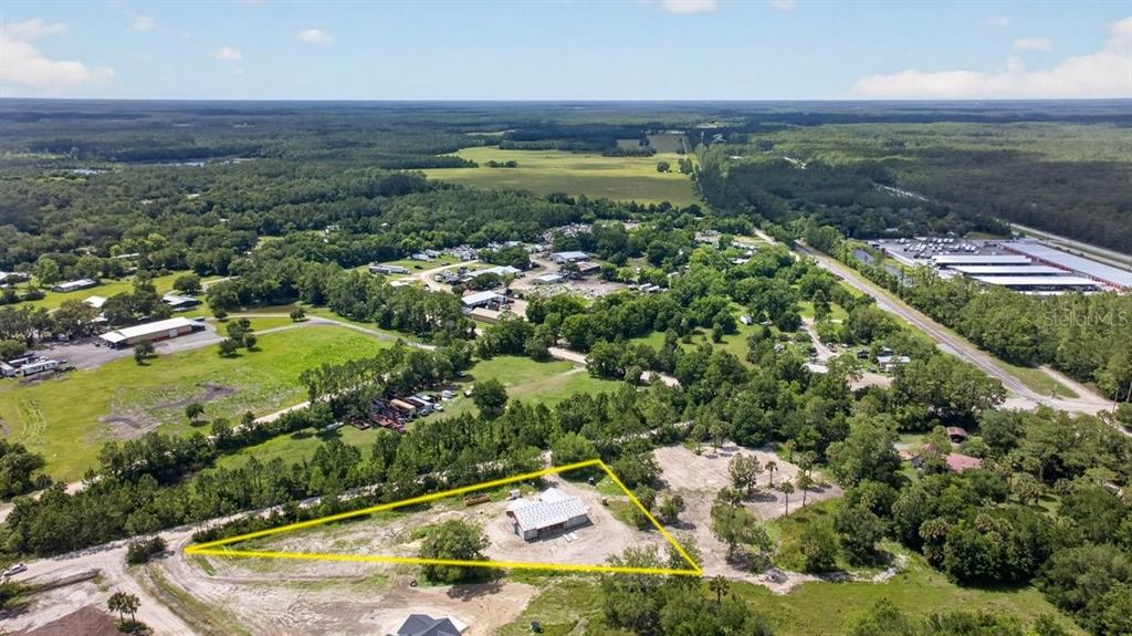 An aerial view shows a single-story building situated on a large, partially cleared triangular lot — 31 FAVORETTA ROAD, BUNNELL, FL
