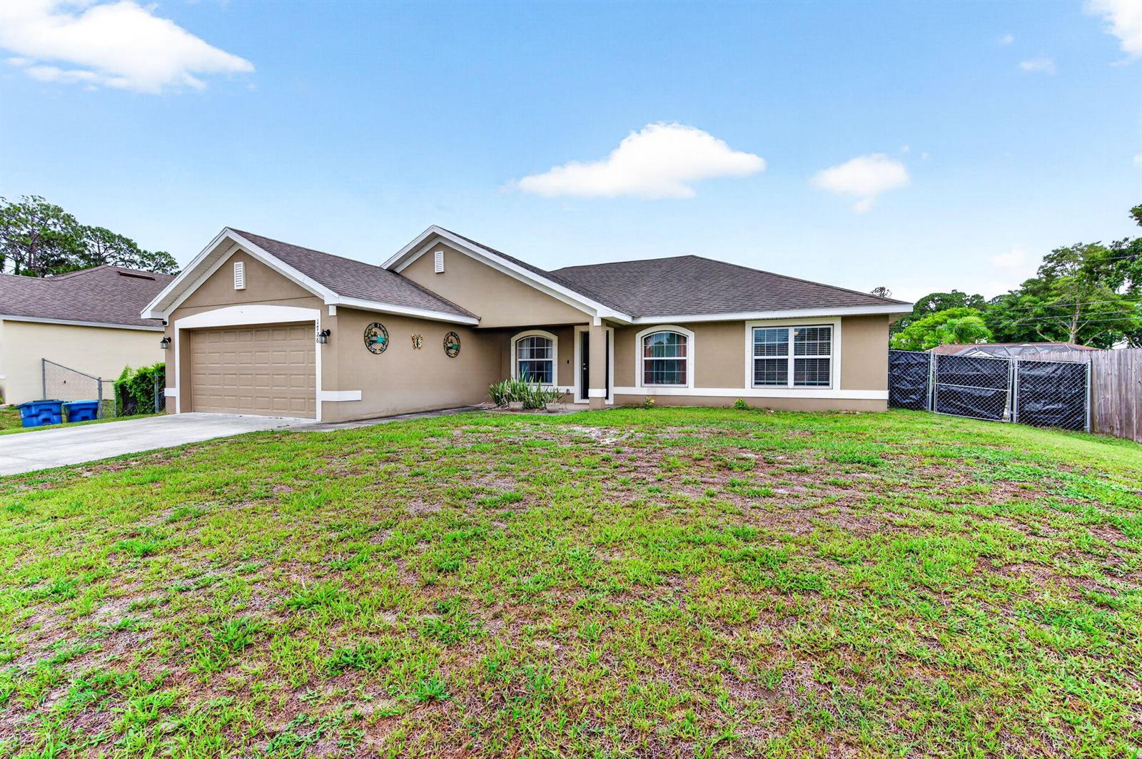 A single-story tan house with a two-car garage and a large front lawn — 1726 Pace Drive NW, Palm Bay FL 32907, PALM BAY, FL