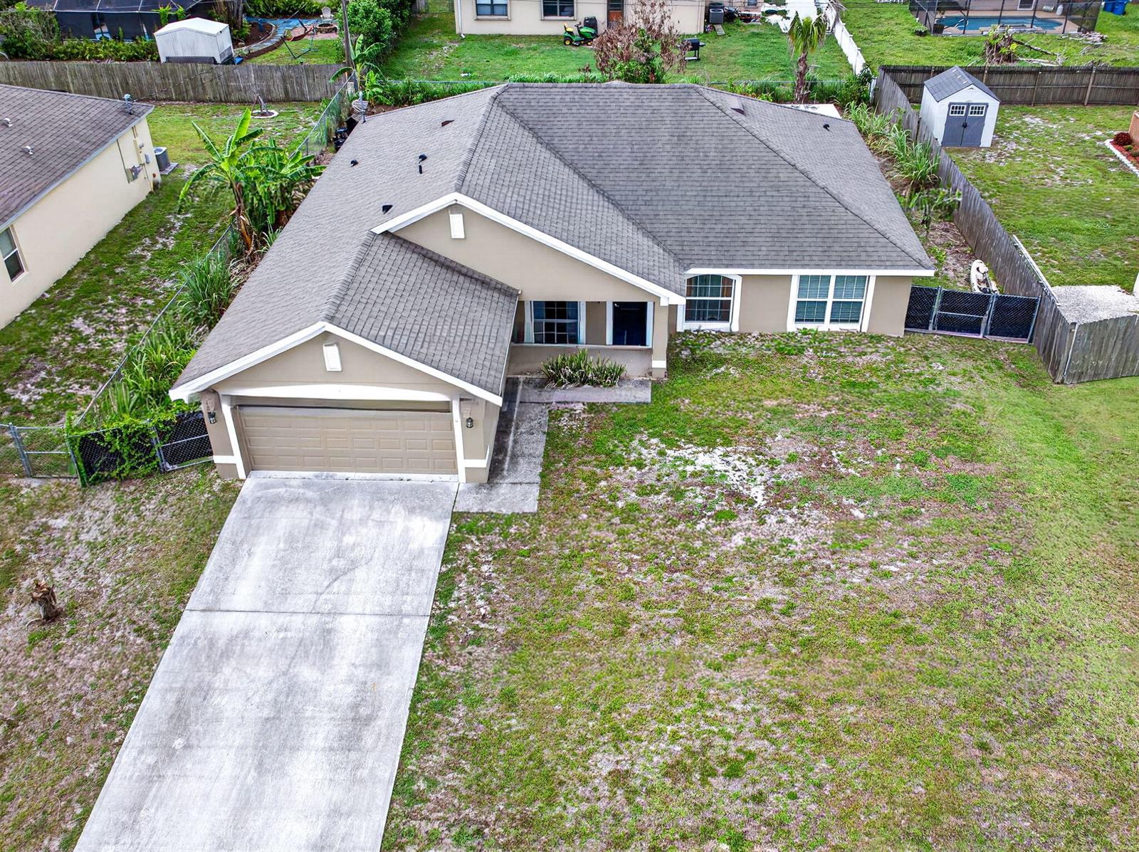An aerial view shows a single-story house with a garage, driveway, and a fenced yard — 1726 Pace Drive NW, Palm Bay FL 32907, PALM BAY, FL