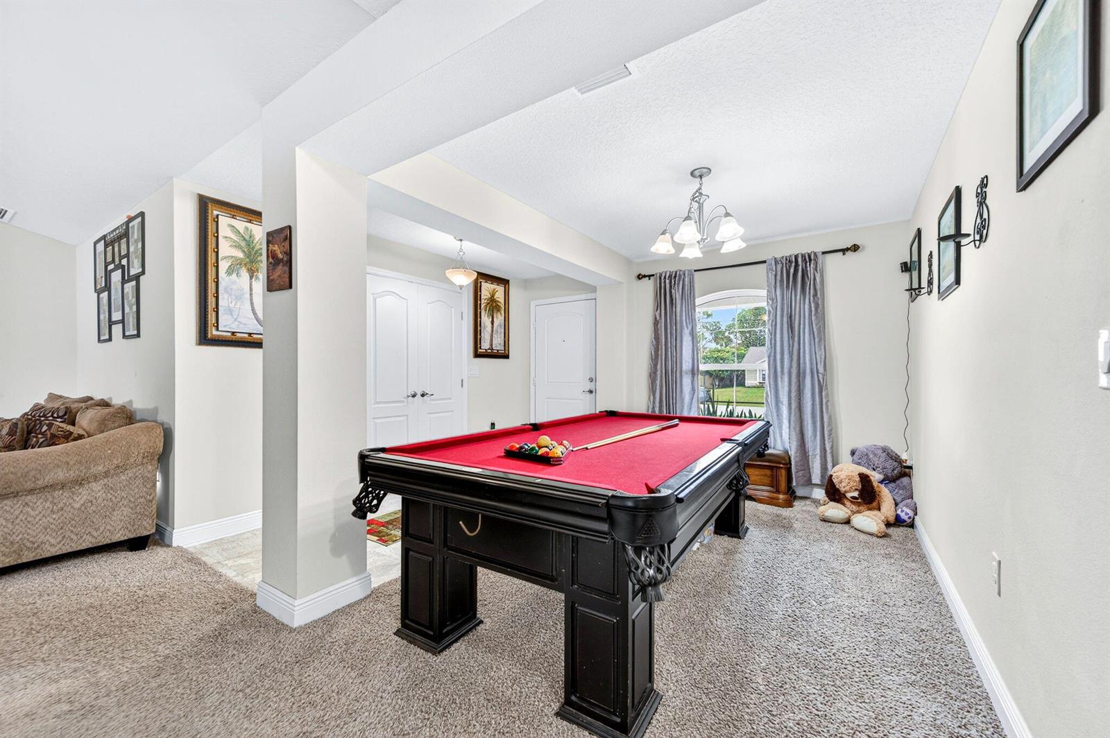 A game room features a red-felt pool table, beige carpeting, and a chandelier — 1726 Pace Drive NW, Palm Bay FL 32907, PALM BAY, FL