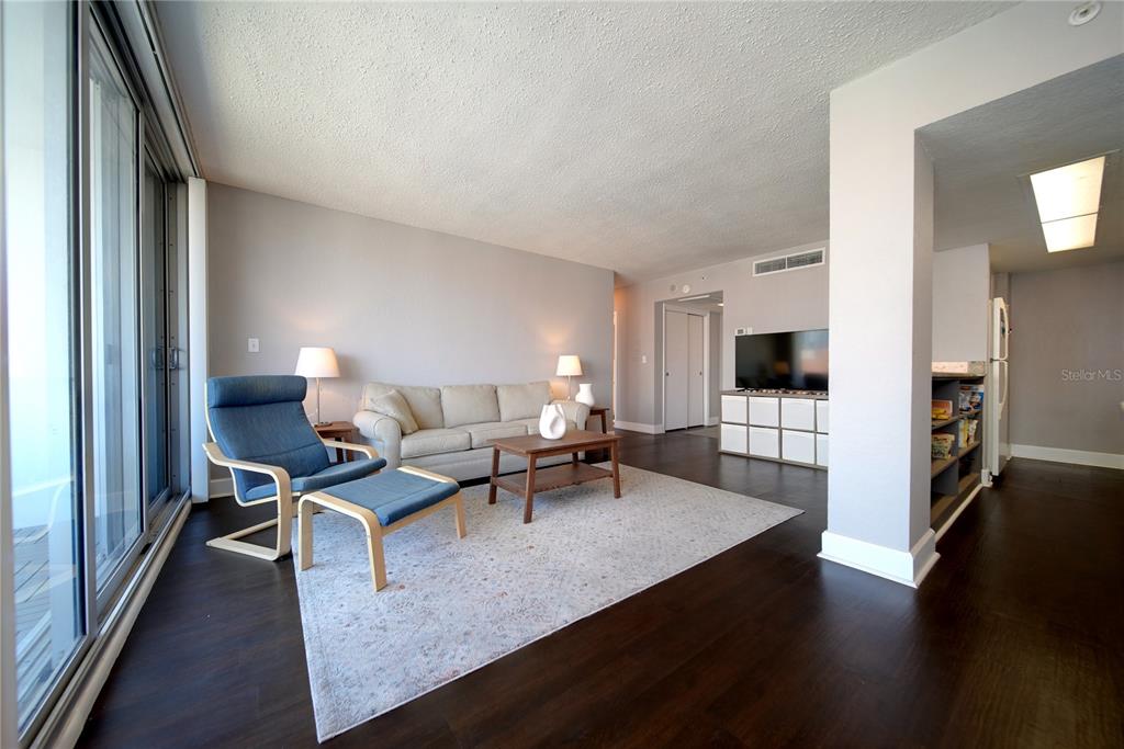 A living room with dark wood floors, a beige sofa, and a blue lounge chair — 470 3RD STREET S UNIT 612, ST PETERSBURG, FL