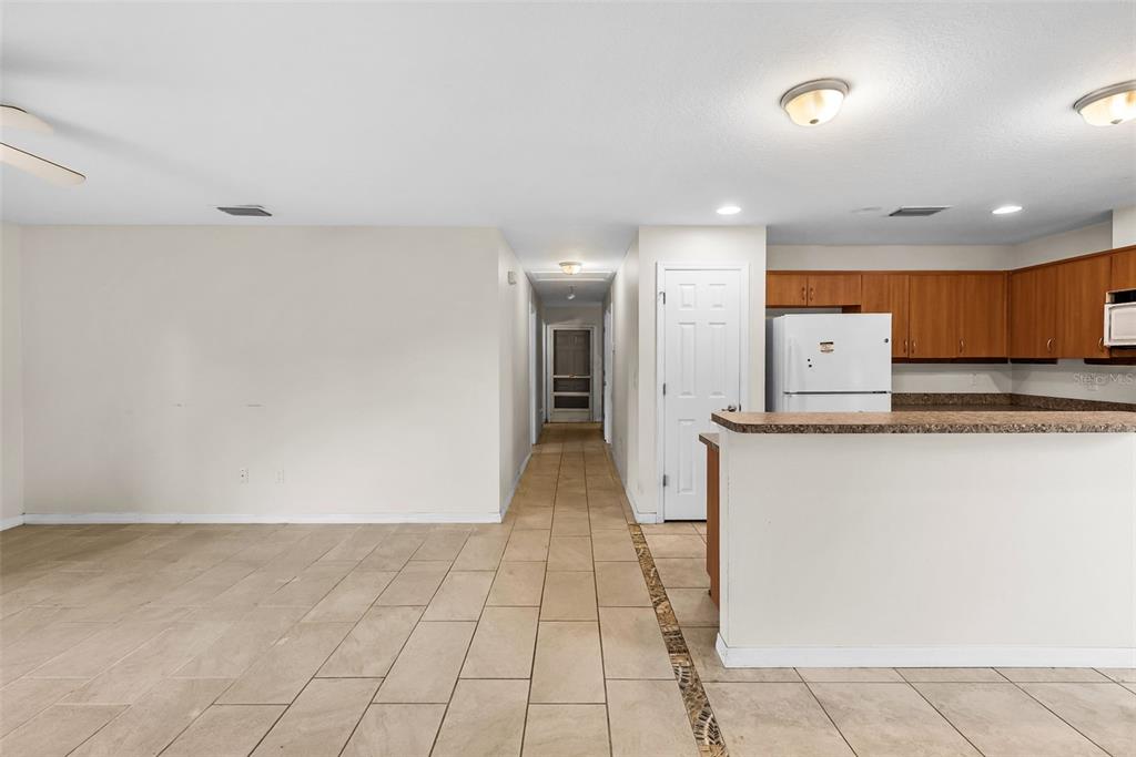A tiled living area opens to a kitchen with wooden cabinets and a breakfast bar — 5451 MAC ARTHUR AVENUE, NEW PORT RICHEY, FL