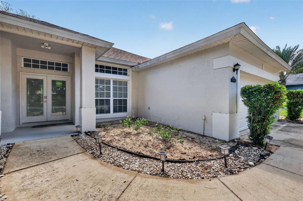 The exterior of a house features a front entrance, a window, and a landscaped bed — 39914 SUNBEAM WAY, LADY LAKE, FL