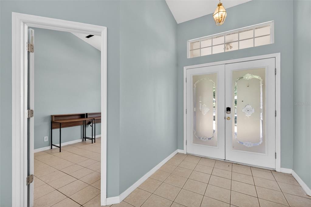 An entryway with tile flooring, light blue walls, and double glass-paneled front doors — 39914 SUNBEAM WAY, LADY LAKE, FL