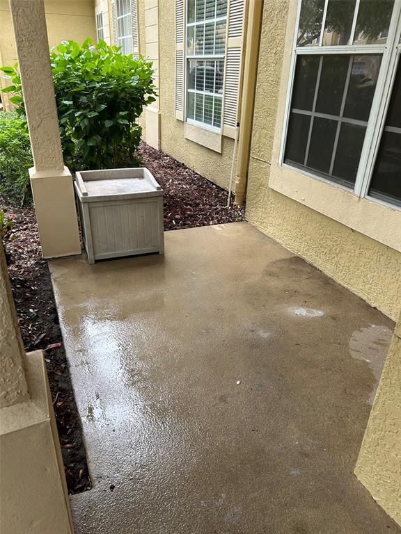 A concrete patio area sits beside a building exterior with a window and shrubbery — 823 GRAND REGENCY POINT UNIT 102, ALTAMONTE SPRINGS, FL