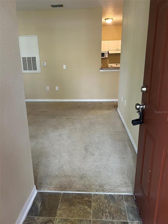 An interior view shows a carpeted living area adjacent to a kitchen with white cabinets — 823 GRAND REGENCY POINT UNIT 102, ALTAMONTE SPRINGS, FL
