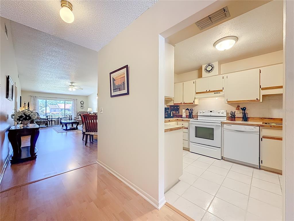 A view from a hallway looking into a kitchen with white appliances and a living area — 3505 TARPON WOODS BLVD UNIT P408, PALM HARBOR, FL