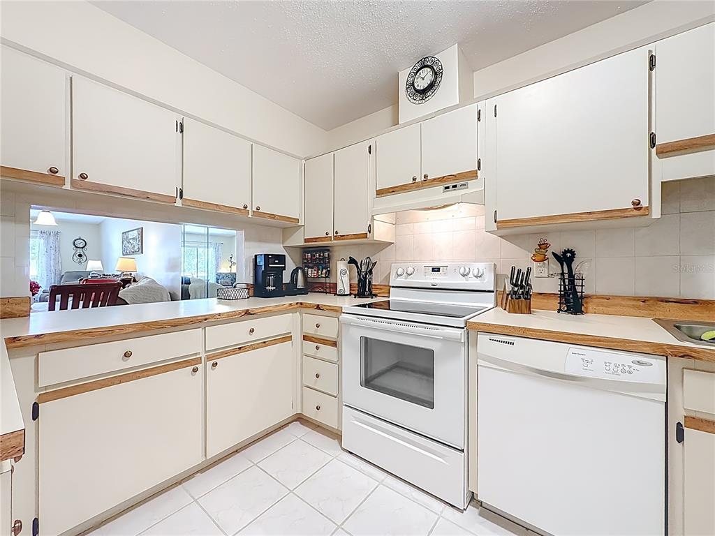 A kitchen with white cabinets, light-colored countertops, white appliances, and tiled flooring — 3505 TARPON WOODS BLVD UNIT P408, PALM HARBOR, FL