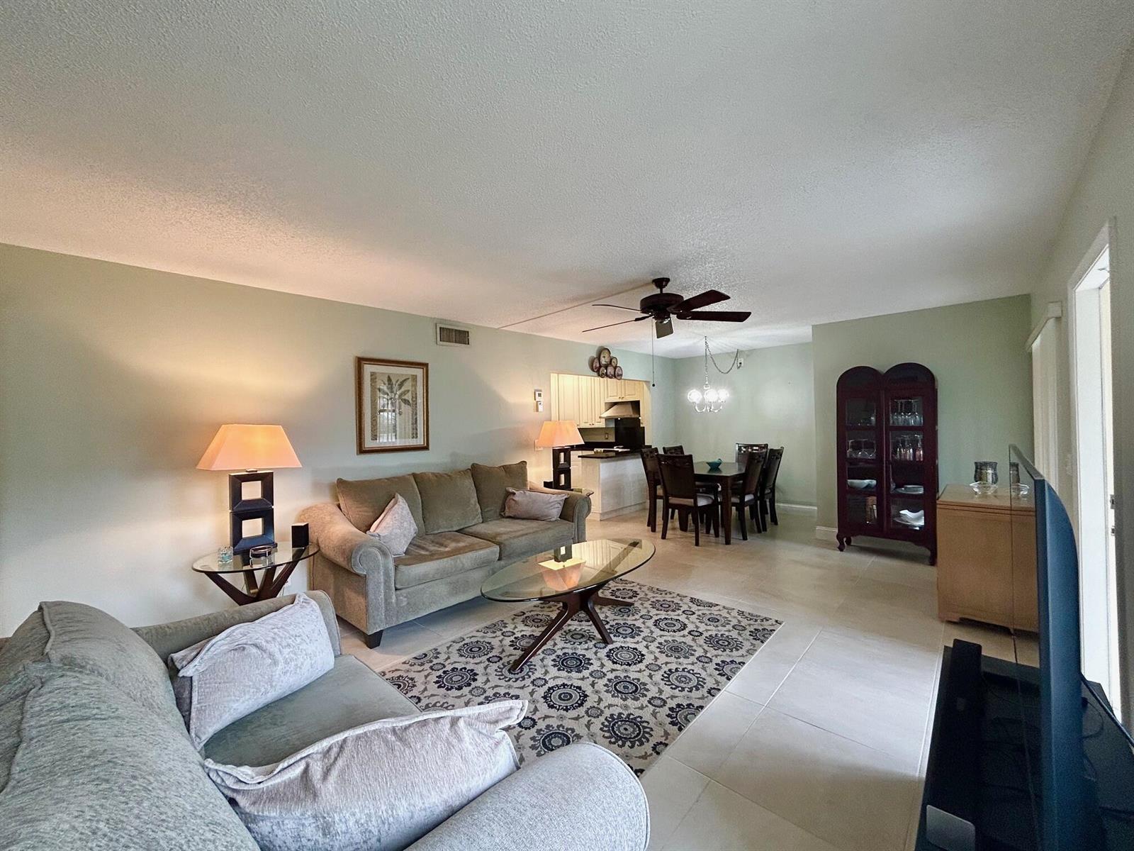 A living room and dining area with light green walls, tile flooring, and neutral furniture — 140 Lake Pine Circle # 1, FL 33463, FL