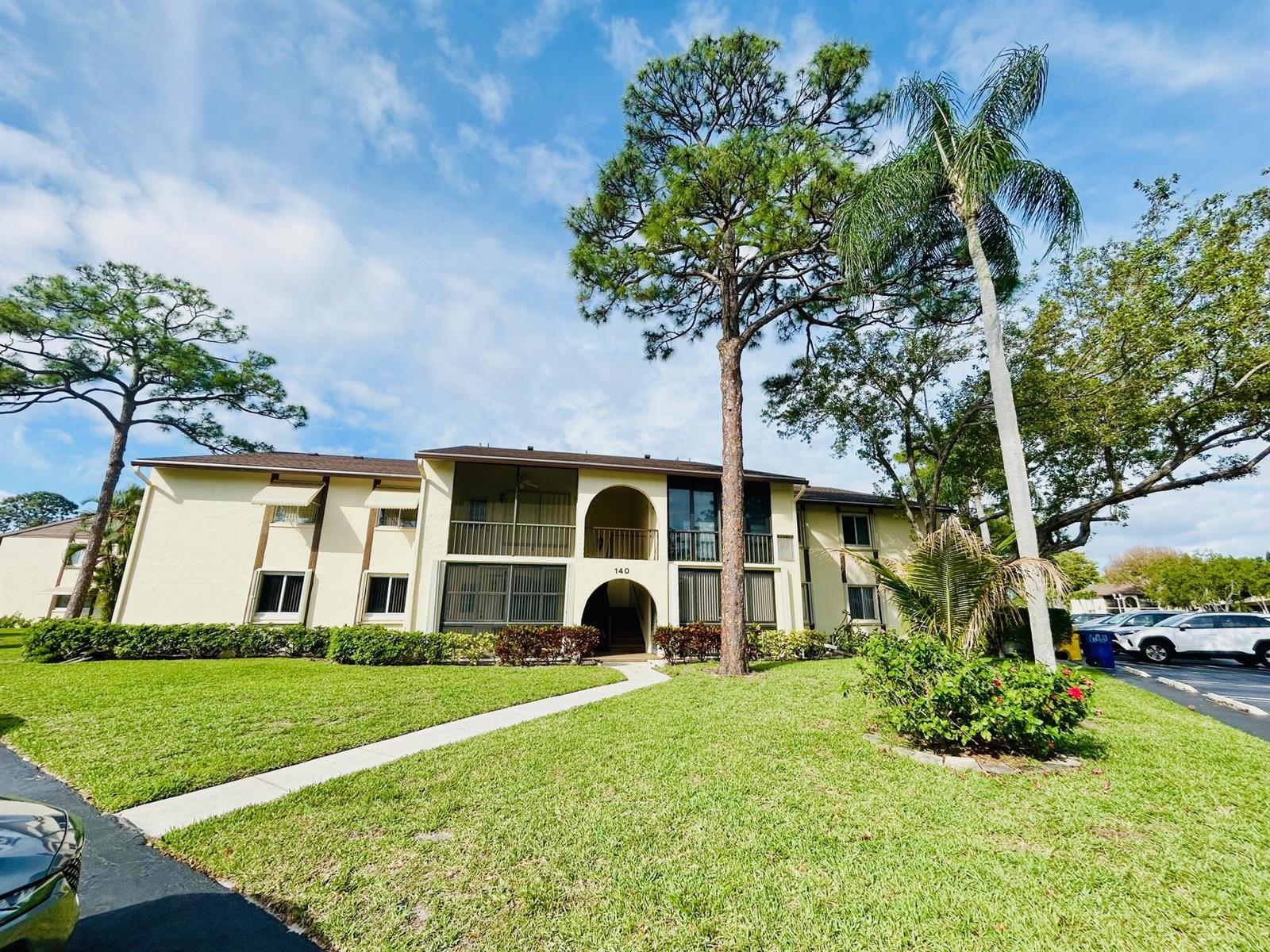 A sunroom features tile flooring, a ceiling fan, wicker chairs, and large windows with blinds — 140 Lake Pine Circle # 1, FL 33463, FL
