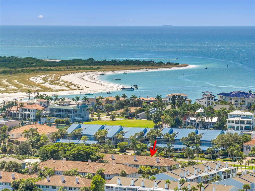 An aerial view shows a coastal neighborhood with a red arrow pointing to a townhouse — 903 PINELLAS BAYWAY S UNIT 302, TIERRA VERDE, FL