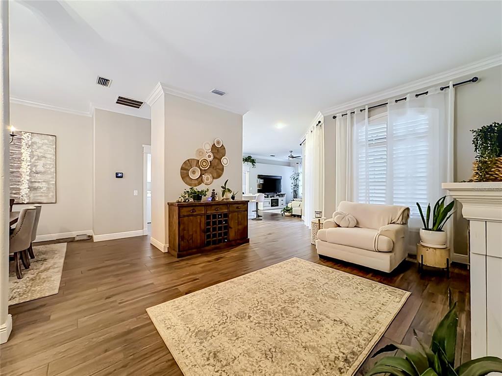 An open-concept living area features wood flooring, a wooden sideboard, and a neutral-toned armchair — 3605 ELK RIDGE LANE, VALRICO, FL