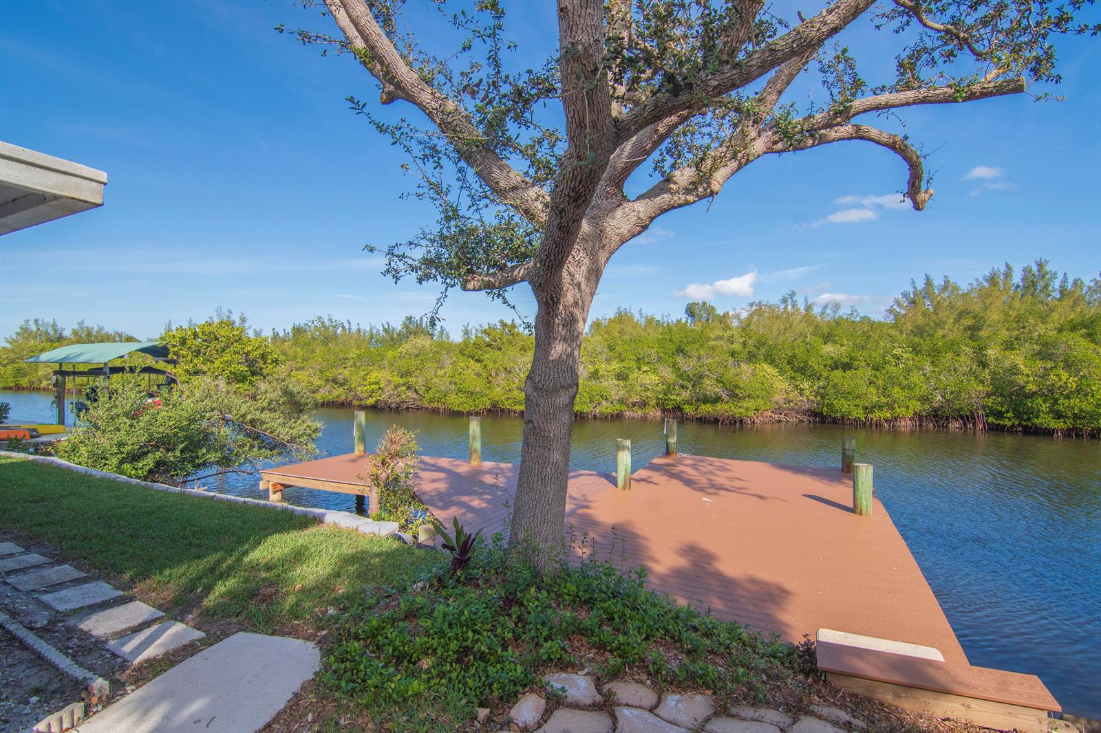 A wooden dock extends into a canal surrounded by lush mangroves under a clear sky — 922 Jackson Way, Fort Pierce FL 34949, FORT PIERCE, FL