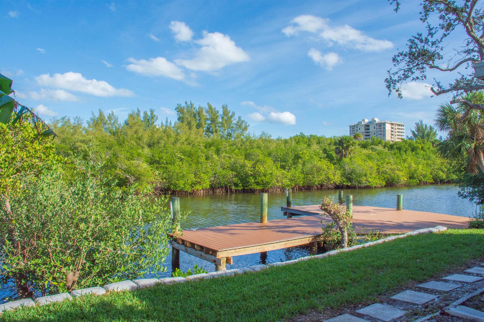 A wooden dock extends into a calm canal surrounded by lush green mangroves and trees — 922 Jackson Way, Fort Pierce FL 34949, FORT PIERCE, FL