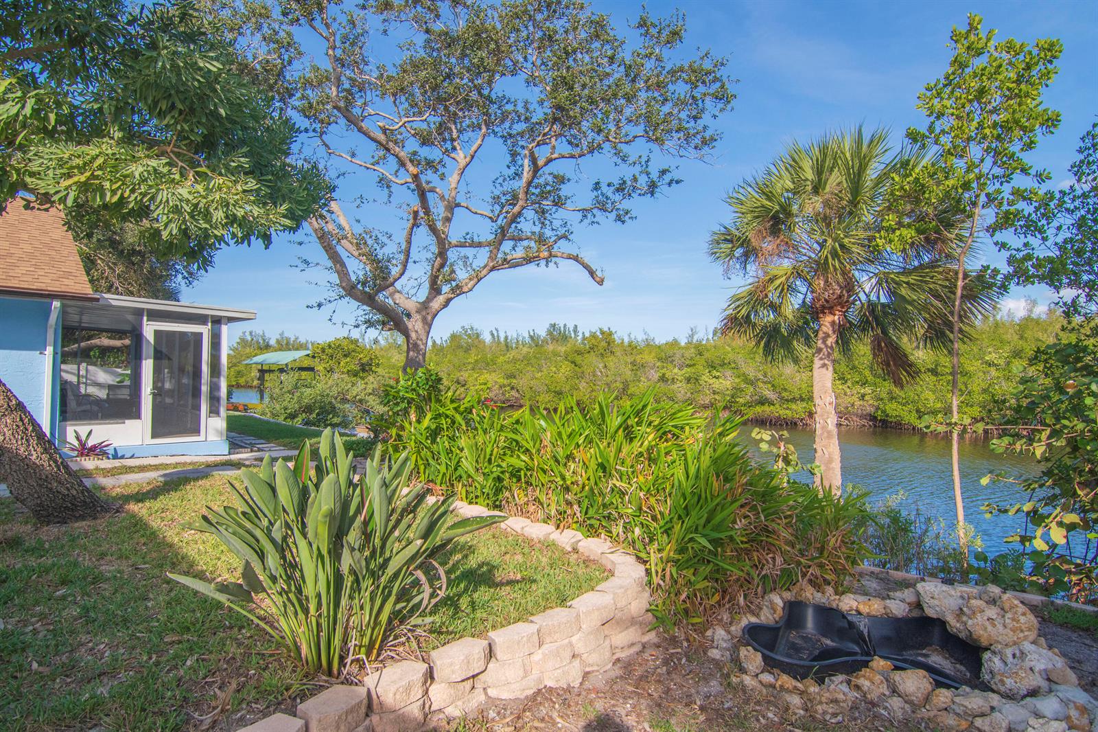A backyard features a stone-bordered garden, a small pond, and a view of a canal — 922 Jackson Way, Fort Pierce FL 34949, FORT PIERCE, FL