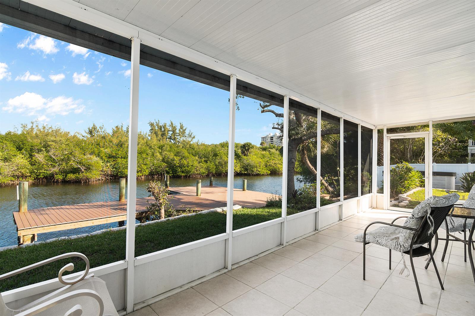 A screened-in porch with tile flooring overlooks a wooden dock on a canal — 922 Jackson Way, Fort Pierce FL 34949, FORT PIERCE, FL