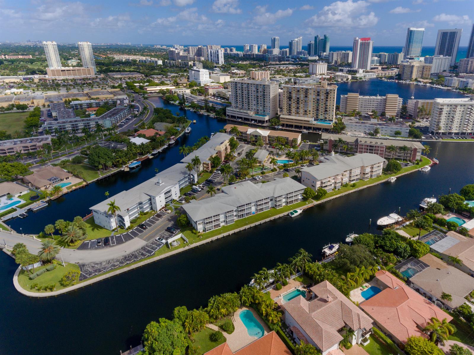 Aerial view of a waterfront apartment complex with swimming pools and surrounding residential buildings — 465 Paradise Isle Boulevard # 110, Hallandale Beach FL 33009, HALLANDALE BEACH, FL