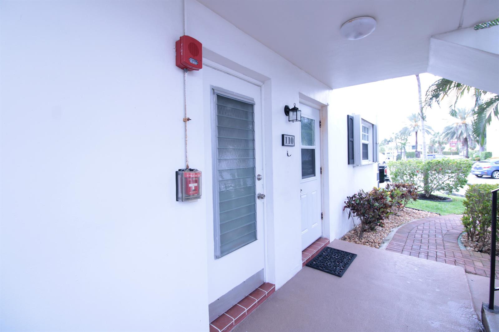 An exterior view of a building entrance with a fire alarm and unit number 110 — 465 Paradise Isle Boulevard # 110, Hallandale Beach FL 33009, HALLANDALE BEACH, FL